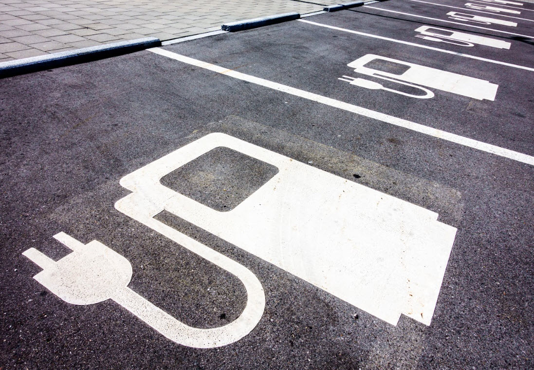 A series of parking spots with electric vehicle graphics painted on them