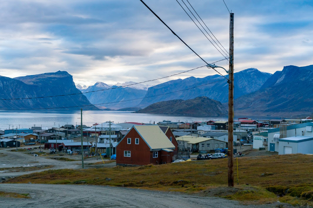 A remote community of small homes bordering a lake and surrounded by mountains