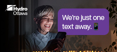 On the left: a photo of a smiling older woman holding a phone by a window with twinkling lights reflecting with text that says 'We’re just one text away. Report an outage and register for alerts—all via text!' On the right, it explains: 'Communication is a two-way street. Now you can register for outage alerts or report an outage by sending us a text message. Convenient updates and interactive messaging—it’s all available via text.' Instructions are included: 'Text 'REG' to PWROUT (797688) to register for alerts' and 'Text 'OUT' to PWROUT (797688) to report an outage. For more information on outage alerts, visit hydroottawa.com/alerts