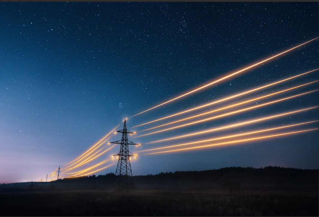 Transmission towers with glowing yellow powerlines on a starry night