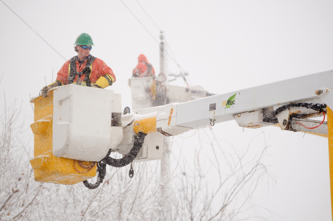 Two hydro workers in buckets make repairs in a snow storm
