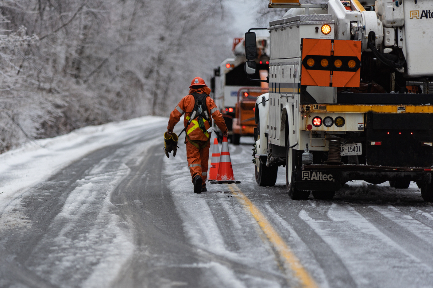 A hydro worker puts out safety pilons along an icy road