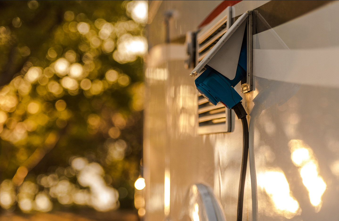 An electric RV charges in the woods
