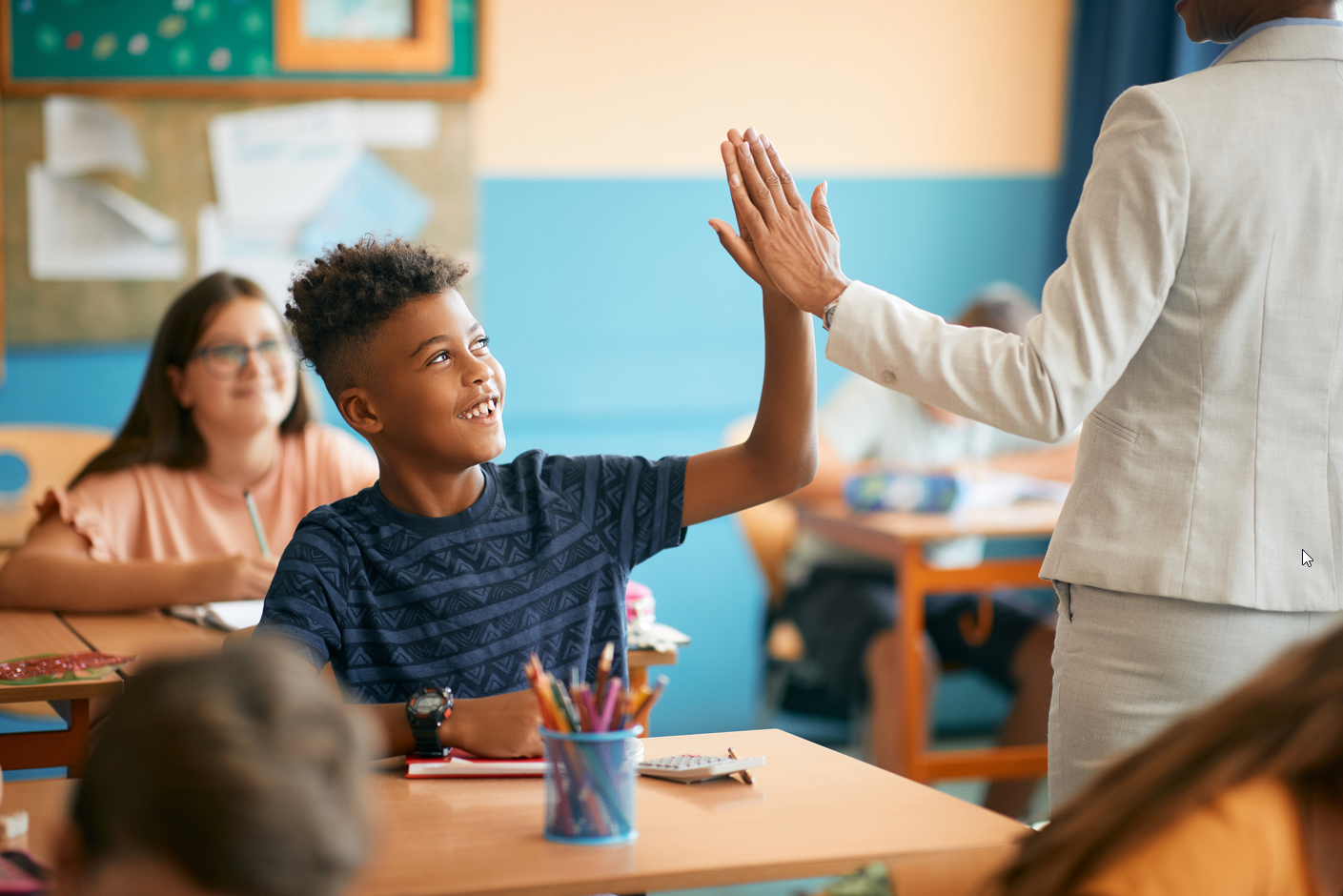 A young boy high-fives his teacher in class