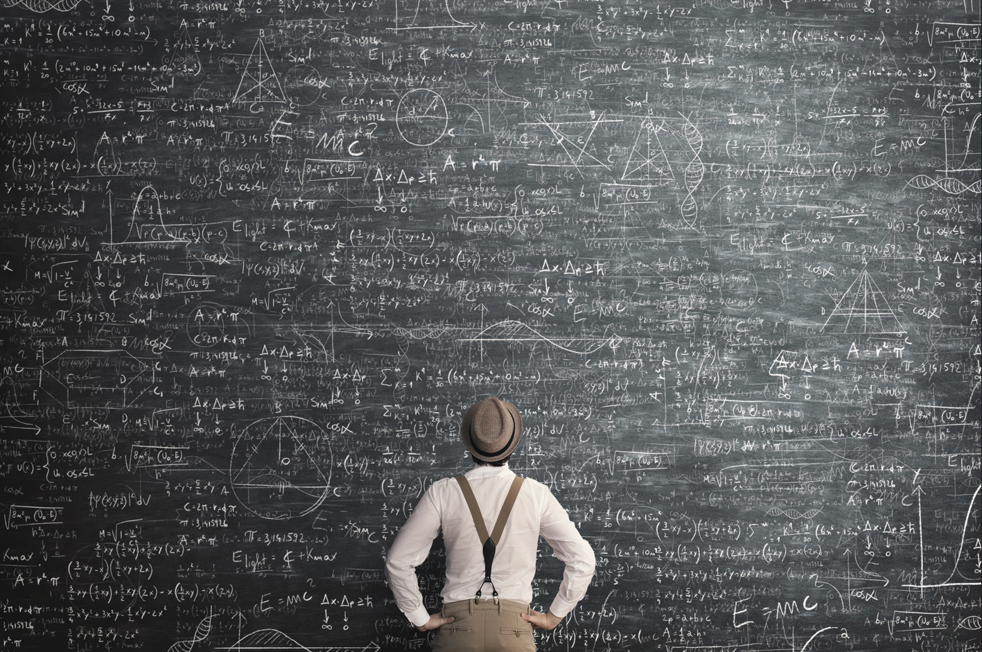 A man wearing a hat and suspenders looks at a blackboard covered in complex mathematical formulas
