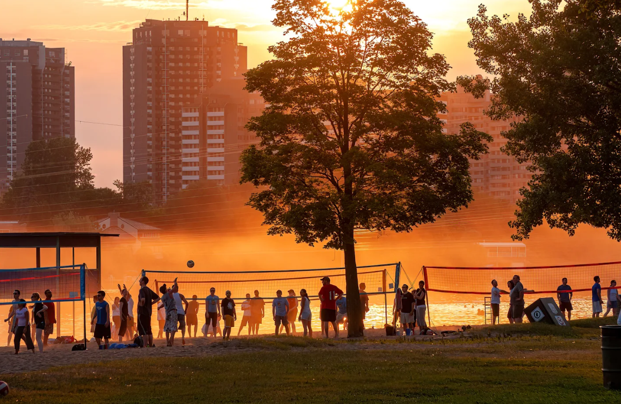 Beachgoers and volleyball players at dusk at Mooney's Bay in Ottawa