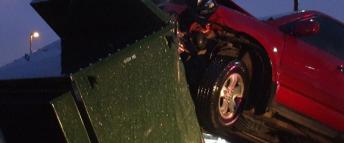 A red car colliding with a green electric transformer
