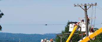 Multiple Hydro Ottawa power line maintainers repairing damaged hydro poles on a busy street