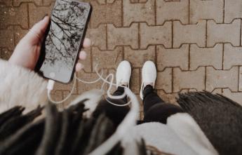 POV image of someone holding an iphone and looking down at their feet