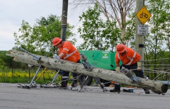 Hydro crews lift a broken pole off the road