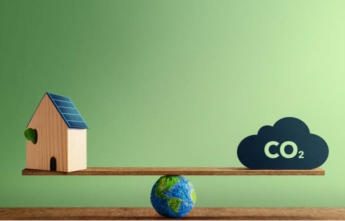 A scale with a small wooden house on one side and a cloud with CO2 on the other.