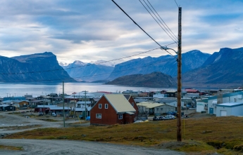 A remote community of small homes bordering a lake and surrounded by mountains