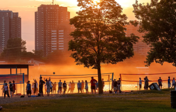 Beachgoers and volleyball players at dusk at Mooney's Bay in Ottawa