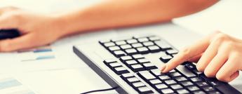 Woman's hands typing on a keyboard and using a mouse