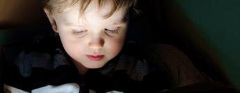 A child looking at a tablet in a dark room