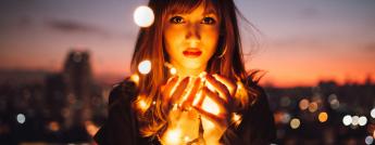 Woman holding lights against the backdrop of a city alight at night