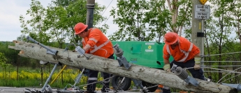 Hydro crews lift a broken pole off the road