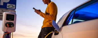 A young man browses on his phone while his vehicle charges