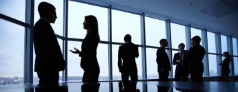 Group of colleagues standing against a window in the office and speaking