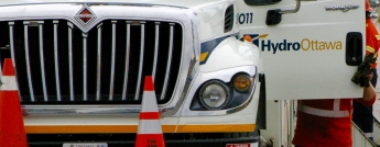 A worker holds the door open to a bucket truck with the Hydro Ottawa logo on it
