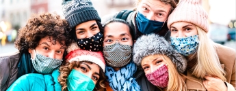 A group of young people in winter clothing and face masks pose together
