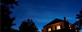 A lit house at night against a starry sky