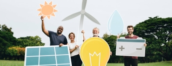 Four people hold up cardboard signs such as the sun, a wind turbine, solar panel, light bulb and battery