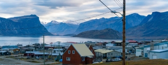 A remote community of small homes bordering a lake and surrounded by mountains