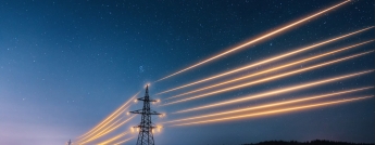 Transmission towers with glowing yellow powerlines on a starry night