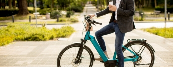 A young man on an electric bike holding a coffee
