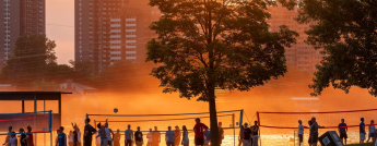 Beachgoers and volleyball players at dusk at Mooney's Bay in Ottawa