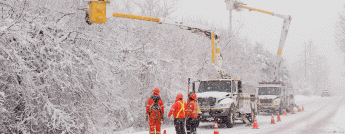 Hydro crews working in bucket trucks along a snowy road