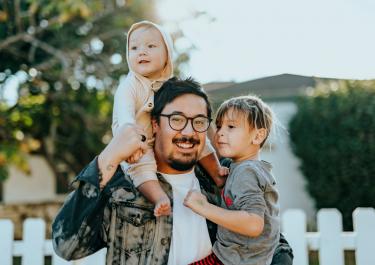 Father carrying his kids outside in the backyard